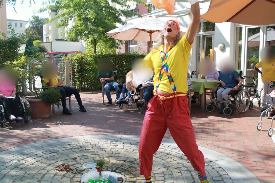 Karl jongliert im Garten vor Bewohnerinnen und Bewohnern